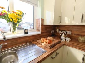 A kitchen with a sink, kettle, clock and bread on a cutting board at 46 Chafeys Avenue 