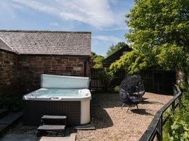 A garden with a hot tub and an outdoor chair at Carwinley Mill House Cottage in Carwinley near Longtown