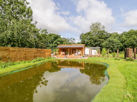 An outdoor area with a pond and a wooden cabin at The Chard in Carlisle