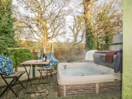 An outdoor area with a hot tub and champagne on a table at The Heronry in Carlisle