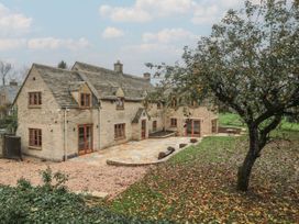 A stone house with a garden and patio at Manor Cottage in Carterton, Oxfordshire