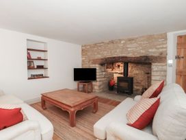 A living room with a sofa, coffee table, and television at Manor Cottage in Carterton, Oxfordshire