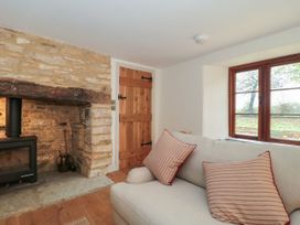 A living room with a stone fireplace and wooden door at Manor Cottage in Carterton, Oxfordshire