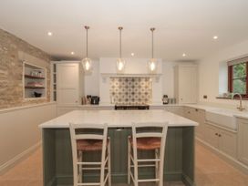 A kitchen with an island and stools at Manor Cottage in Carterton, Oxfordshire