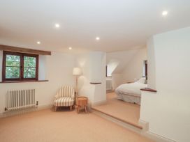 A bedroom with a bed, armchair, and window at Manor Cottage, Carterton, Oxfordshire