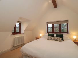A bedroom with a bed and windows at Manor Cottage in Carterton, Oxfordshire