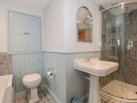 A bathroom with a shower, toilet, sink, and storage cabinet at Manor Cottage, Carterton, Oxfordshire