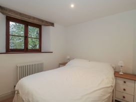A bedroom with a bed and nightstands at Manor Cottage in Carterton, Oxfordshire