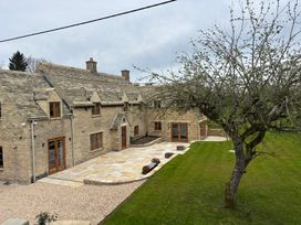 An outdoor view of a house with a patio and tree at Manor Cottage in Bampton, Oxfordshire