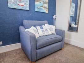 A living room with an armchair and paintings at Hornblower Lodge in Whitby