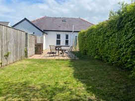 A garden with a house, patio table, chairs, and a swing set at Kenvor Newport, Pembrokeshire