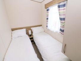 A bedroom with two single beds and a lamp at 82 Manorbier Park in Manorbier