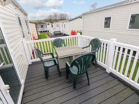 A deck with a table and chairs at 82 Manorbier Park in Manorbier