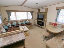 A living room with a sofa and television at 82 Manorbier Park in Manorbier