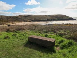 A scenic view of a beach with a bench and hills at 82 Manorbier Park in Manorbier