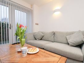A living room with a sofa, flowers, and a table at One Union Mill - garden apartment in Whitby