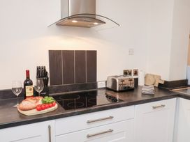 A kitchen with a wine bottle, glasses, and vegetables on the counter at One Union Mill - garden apartment in Whitby