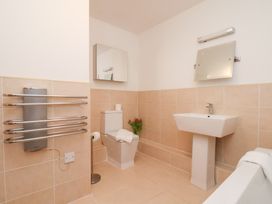 A bathroom with a toilet, sink, and mirror at One Union Mill - garden apartment in Whitby