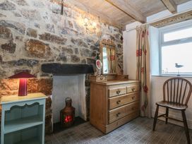 A bedroom with a wooden dresser and stone wall at Parc y Brenin Holidays, Abersoch