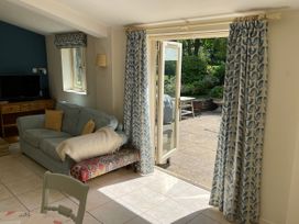 A living room with a sofa and an open door leading to the garden at Meadow Lodge, Cerney Wick near South Cerney, Cotswolds