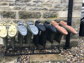 A row of rubber boots on a rack outdoors at Meadow Lodge, Cerney Wick near South Cerney, Cotswolds