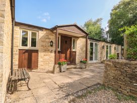 An outdoor area with a stone exterior and bench at Meadow Lodge, Cerney Wick near South Cerney, Cotswolds