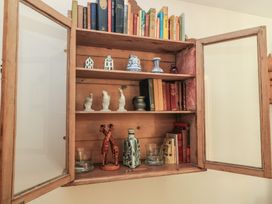 A wooden cabinet with books and decorative items at Meadow Lodge Cerney Wick near South Cerney, Cotswolds