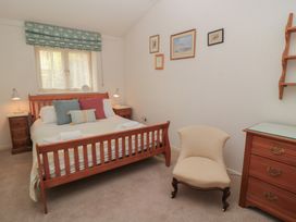 A bedroom with a bed, nightstands, lamps, and decorative frames at Meadow Lodge, Cerney Wick near South Cerney, Cotswolds