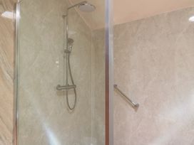 A shower with a showerhead and wall panel at Meadow Lodge Cerney Wick near South Cerney Cotswolds