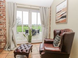 A conservatory with patio doors and seating area at Ivy Barn in Norwich