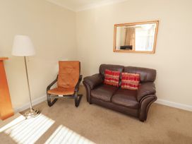 A living room with an armchair and couch at Kittiwake at No 20 Seahouses