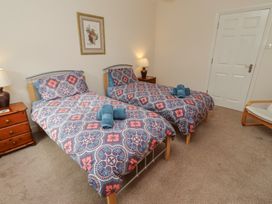 A bedroom with two single beds and a bedside table at Kittiwake at No 20 Seahouses