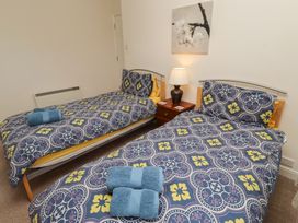A bedroom with two beds and a bedside table at Kittiwake at No 20 Seahouses