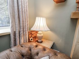 A lamp on a table beside a curtain in a living room at Ingleside Cottage in Whitby