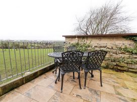 A table and chairs on a patio overlooking grass at Ingleside Cottage in Whitby