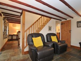 A living room with armchairs and a staircase at Little Blagdon in Beaworthy