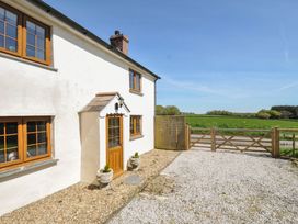 An outdoor view of a house with a gravel path and fence at Little Blagdon Ashwater