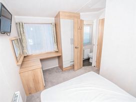A bedroom with a bed, desk, wardrobe and attached bathroom at Devon Cliffs Holiday Park - Holiday Accommodation 14142, Exmouth