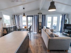 A living room with a sofa and dining area at Lodge 134 Lon Bryn Mair near Bellech