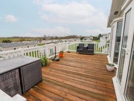 A deck with a chair and table overlooking other properties at Lodge 134 Lon Bryn Mair near Bellech