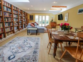 A living room with a bookshelf, sofa, and dining table at Inglewood Bach in Conwy