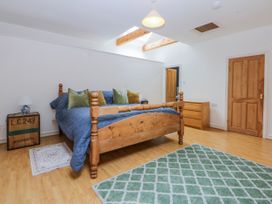 A bedroom with a bed, dresser and lamp at Inglewood Bach Conwy