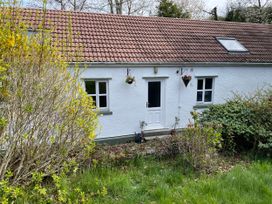 A house with a door and windows surrounded by grass and plants at Inglewood Bach, Conwy