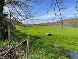 An outdoor view of a grassy field with trees and a fence at Inglewood Bach Conwy