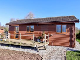A wooden cabin with a deck and potted plants at Star Carr Lakes