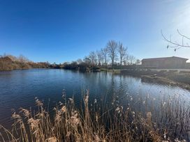 A view of a lake with reeds and a building at Star Carr Lakes