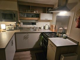 A kitchen with microwave, stove, sink, and utensils at Homeslea 33 Millennium Gardens in Morpeth