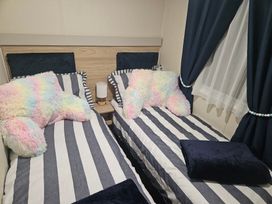 A bedroom with two beds and colorful pillows at Homeslea 33 Millennium Gardens Morpeth