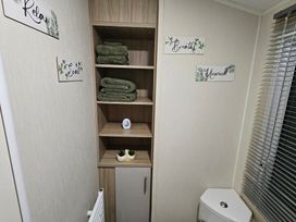 A bathroom with shelves for towels and decorative items at Homeslea 33 Millennium Gardens Morpeth