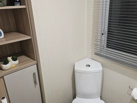 A bathroom with a toilet and shelf at Homeslea 33 Millennium Gardens in Morpeth